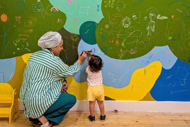 A mother and child doodle on the drawing wall at Play Discover Share