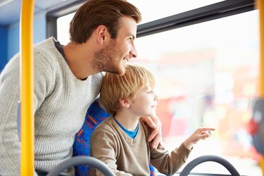 A stock image of a father and son sitting on a bus