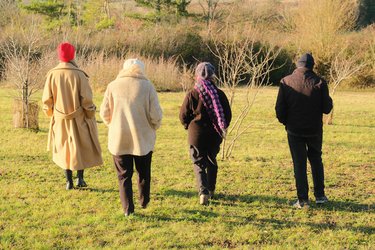 Four people dressed in coats and hats walk through Letchworth fields in winter.