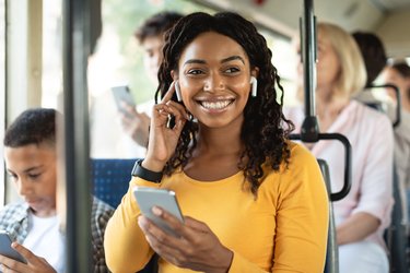 A young person listens to audio through headphones while sitting on a bus.