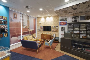 The interior of the museum features a mid-century seating area and a historical shop counter and till.